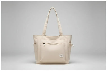 Beige tote bag on denim jacket with phone and clear glass bottle