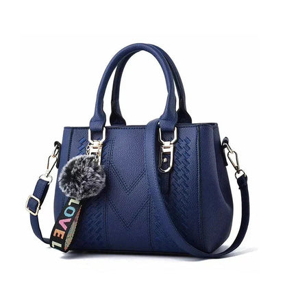 Blue handbag with a decorative keychain on a white background