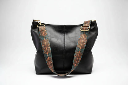 Black leather handbag with decorative brown straps on a white background
