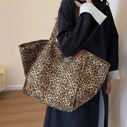 Person holding a leopard print tote bag against a plain background