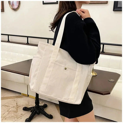 Person holding a white tote bag in an indoor setting