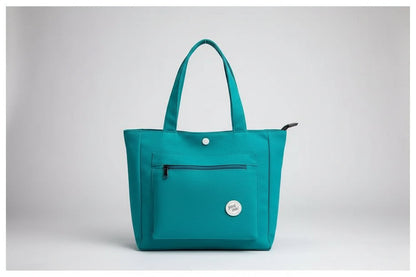 Green jacket and teal bag on a white surface with denim jacket and glass of water.
