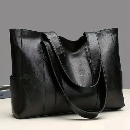 Black leather tote bag on a light gray background