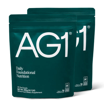 Two green AG1 supplement packages on a white background